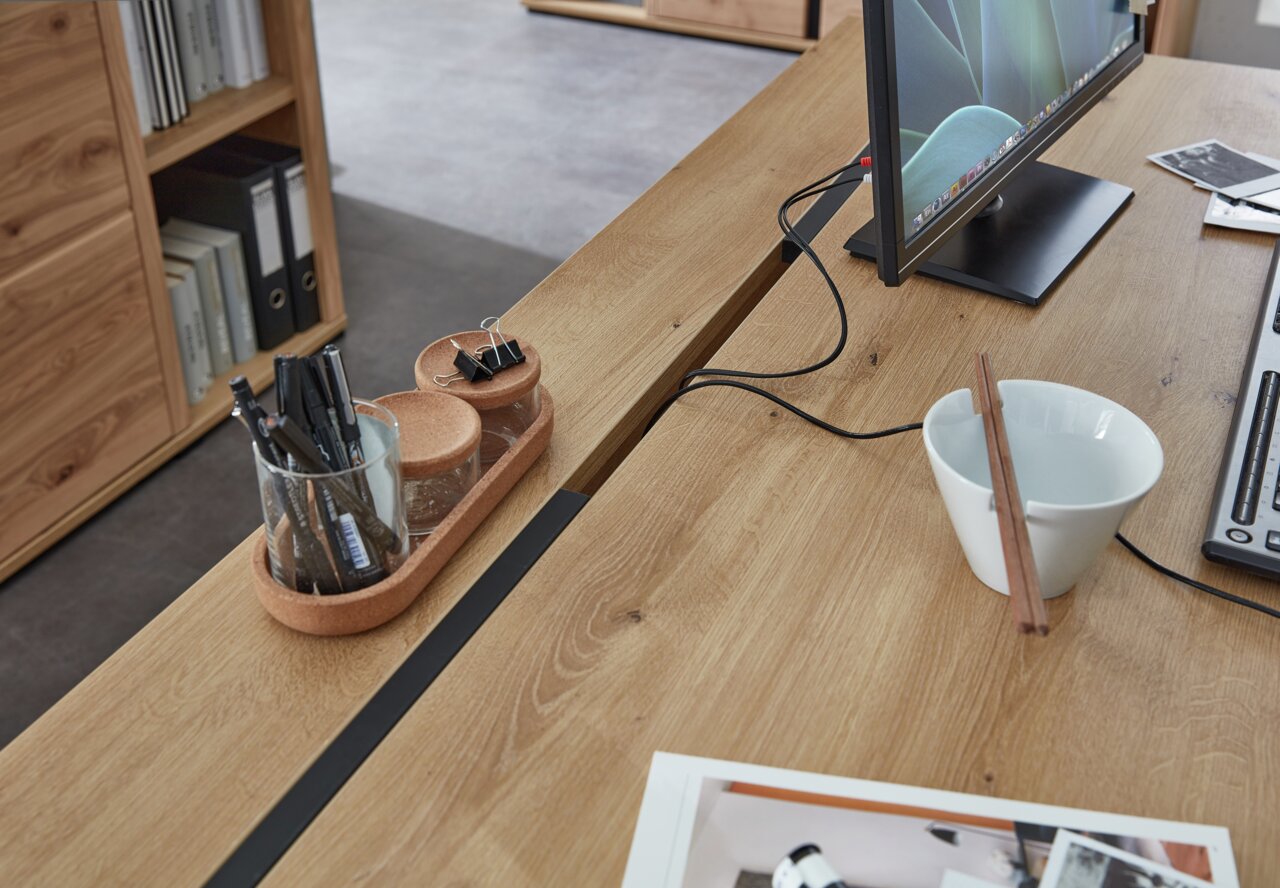 Moderner Schreibtisch aus Holz mit Monitor, Stiftehalter und Schale, seitliche Perspektive