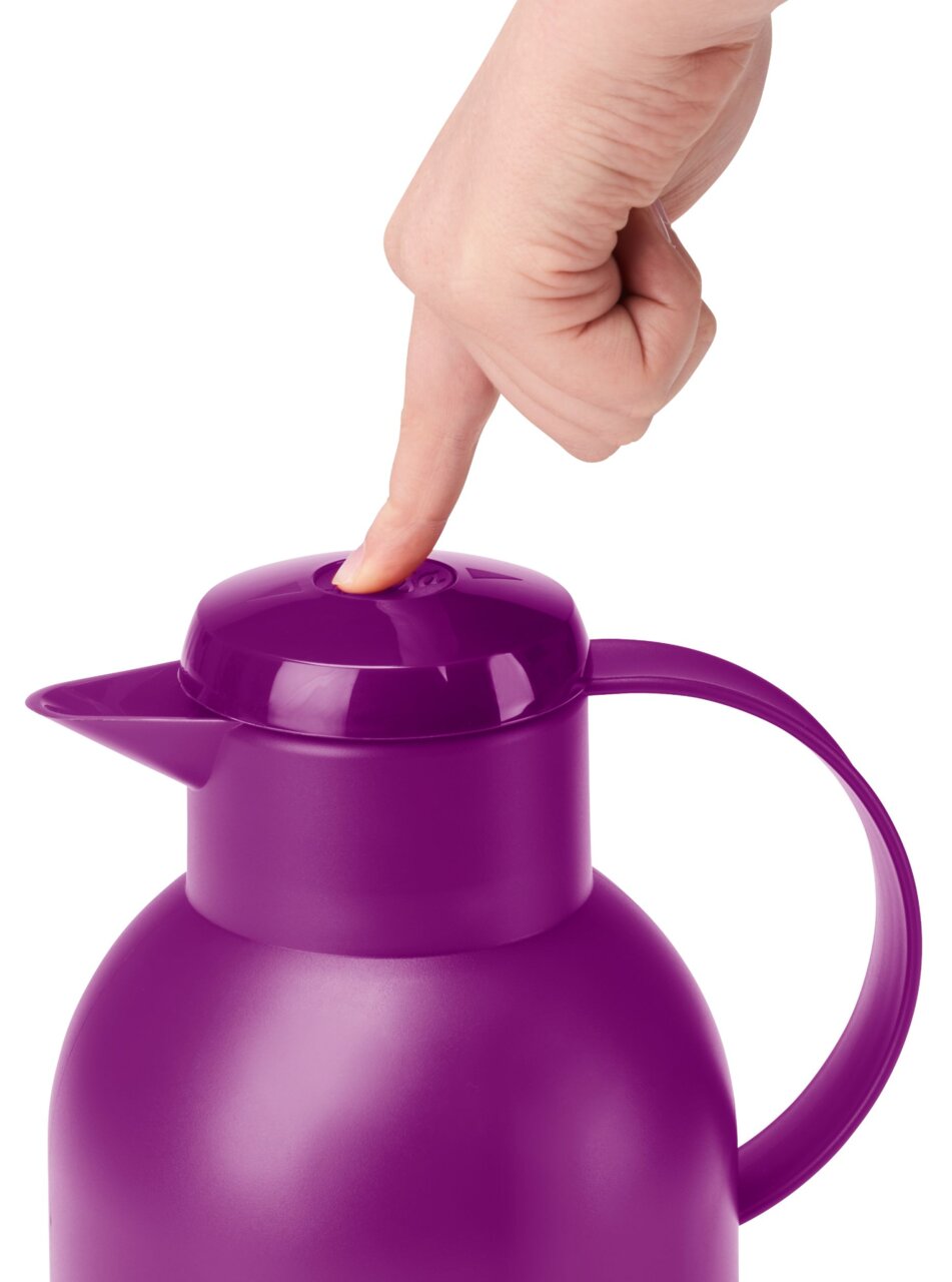 Lila Isolierkanne SAMBA 1,5L, von oben fotografiert, mit einer Hand, die den Deckelknopf drückt.