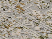 Nahaufnahme eines Designer-Teppichs mit abstraktem Muster in Weiß, Grün und Braun. Die Perspektive zeigt die Textur und das Detail des Teppichs.