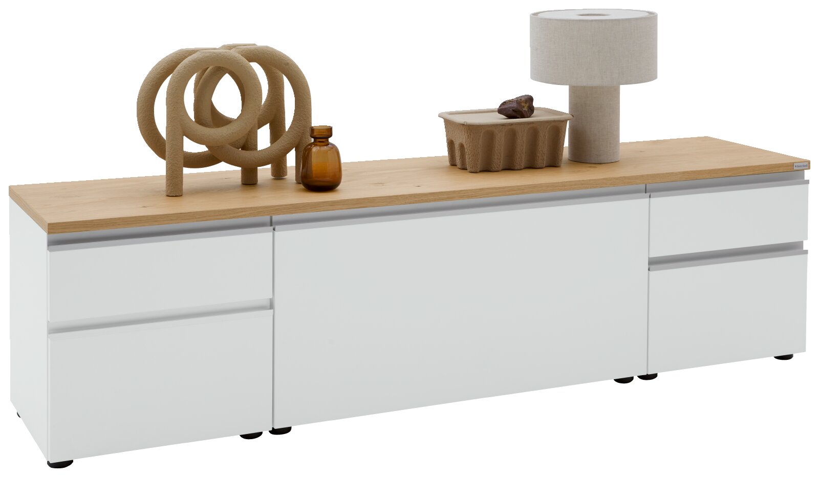 Dieter Knoll Lowboard LENDINA Modernes weißes Sideboard/Lowboard mit Holzplatte und grifflosen Fronten, dekoriert mit Skulptur, Glasflasche, Schale und Tischlampe; Ansicht schräg von vorn (leicht von links) auf weißem Hintergrund.