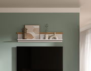 Wandboard mit Dekorationen, darunter Vasen und ein Bild, an einer grünen Wand über einem Fernseher, frontal betrachtet.