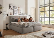 Gemütliches Boxspringbett in einem modernen Schlafzimmer, seitliche Perspektive, mit einer Familie, die darauf entspannt.