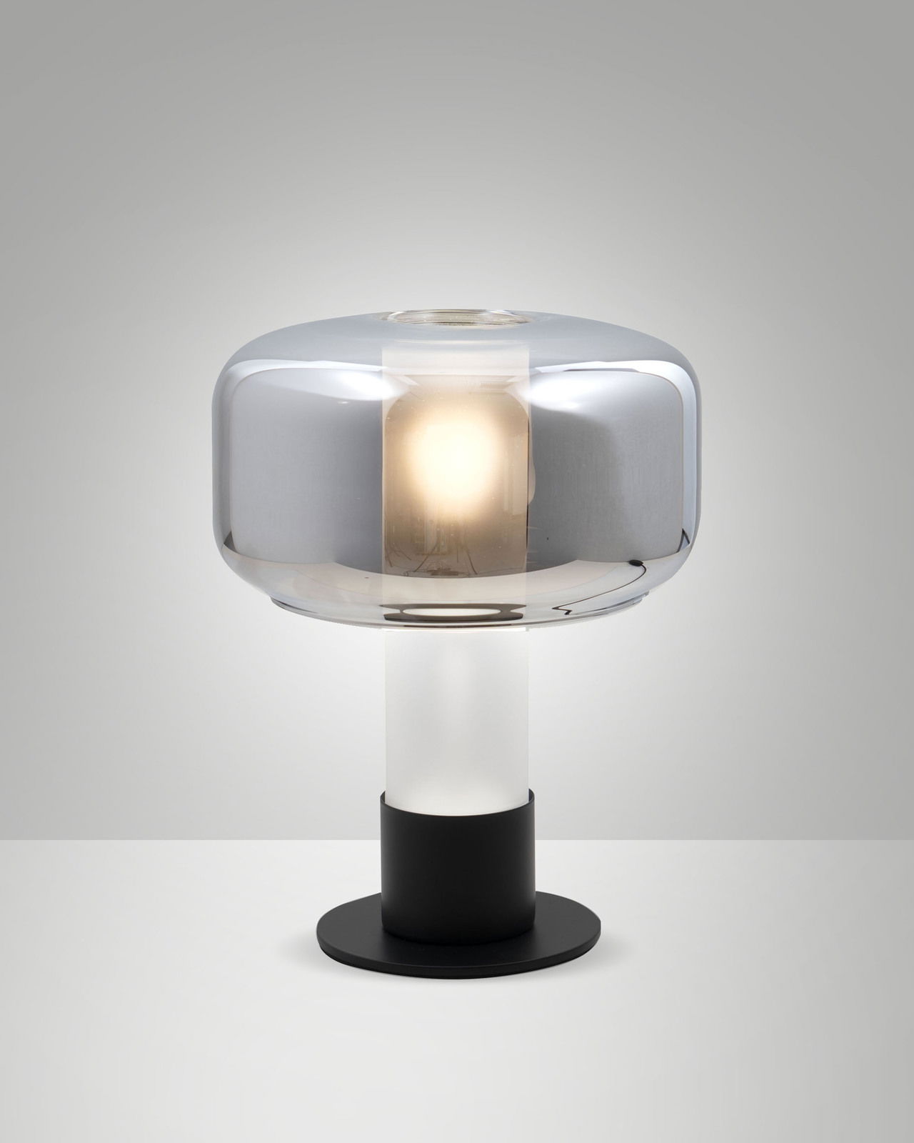 Moderne Tischleuchte mit rundem, silbernem Schirm und schwarzem Sockel, seitliche Perspektive