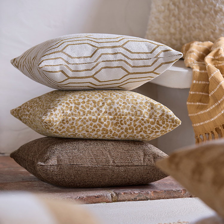 Drei Dekokissen in Braun und Beige mit geometrischem und floralem Muster.