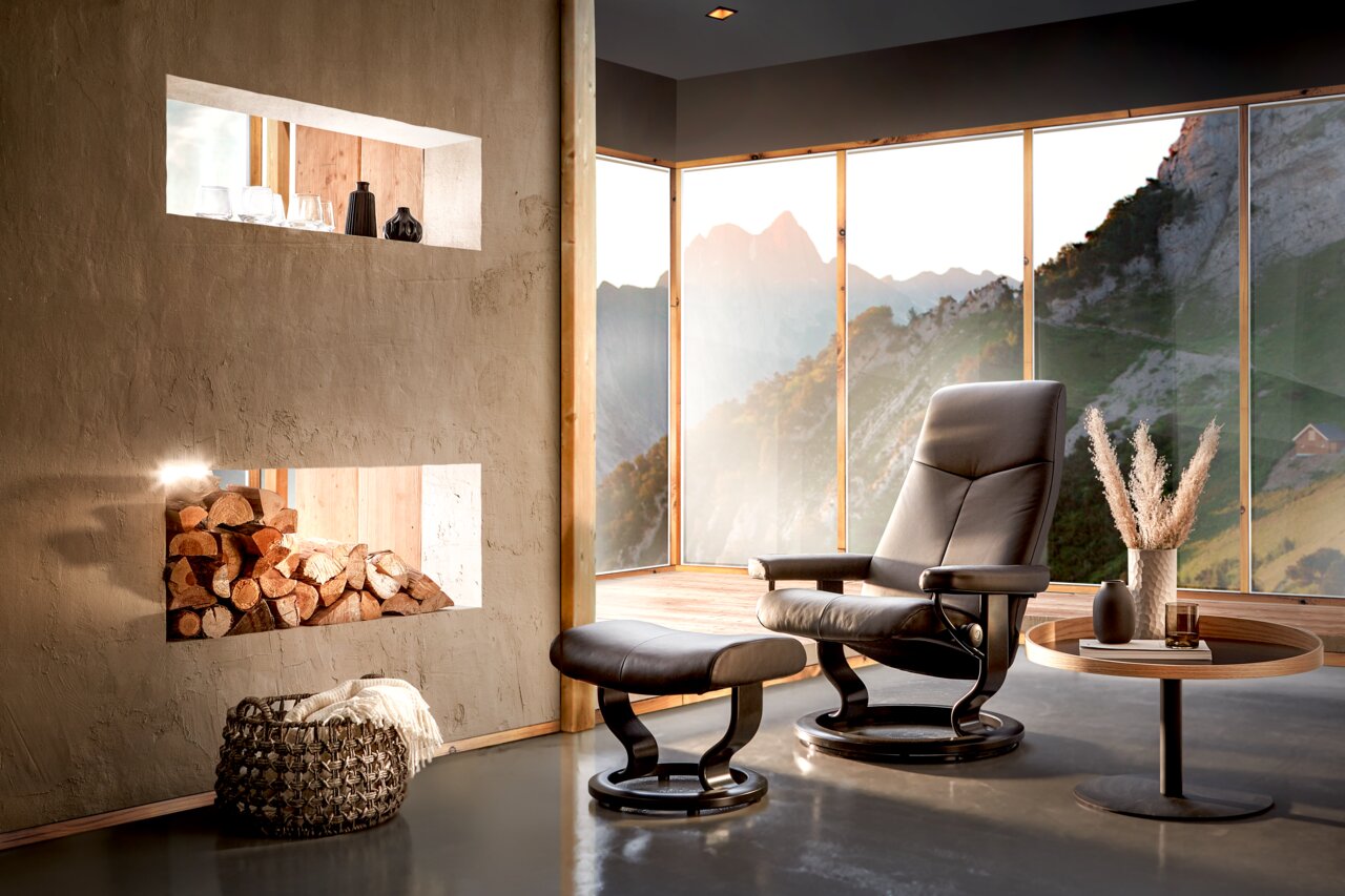 Stressless Einzelsesselset CITY 2020 Moderner Einzelsessel mit Hocker in einem stilvollen Raum mit Panoramafenstern und Bergblick, seitliche Perspektive.