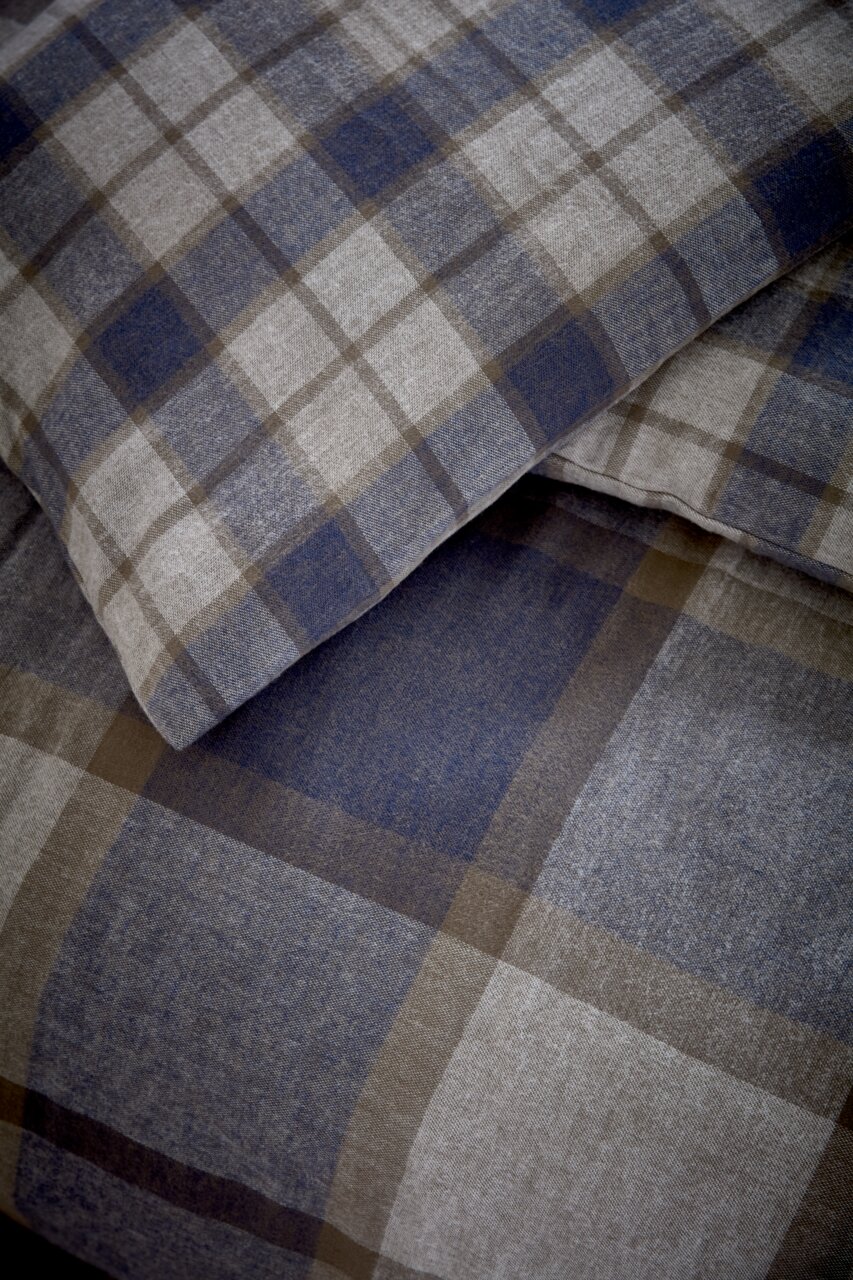 Nahaufnahme von kariertem Bettwäsche-Set in Blau- und Brauntönen, Perspektive von oben