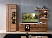 Moderne Wohnzimmermöbel aus hellem Holz mit hoher Vitrine und TV-Lowboard samt beleuchteten Glasfächern, daneben Wandregal mit Deko; frontale Ansicht auf das Möbel-Set.