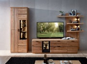 Moderne Wohnzimmermöbel aus hellem Holz mit hoher Vitrine und TV-Lowboard samt beleuchteten Glasfächern, daneben Wandregal mit Deko; frontale Ansicht auf das Möbel-Set.