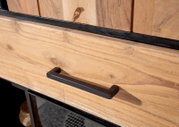 Nahaufnahme eines Highboards aus Holz mit schwarzem Griff, Perspektive von schräg oben