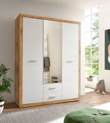 Drehtürenschrank 3-türig in moderner Holz-Optik mit weißen Fronten, frontal abgebildet in einem hellen Raum mit großen Fenstern.