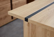 Nahaufnahme eines Schreibtisches aus Holz mit einer schwarzen Metallleiste, seitliche Perspektive.
