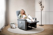 Frau entspannt in einem grauen Relaxsessel, seitliche Perspektive, mit einem Buch in der Hand, umgeben von einem modernen Wohnzimmerambiente.