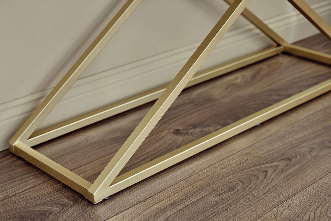 Nahaufnahme der goldenen Metallstruktur einer Konsole auf einem Holzboden, seitliche Perspektive.