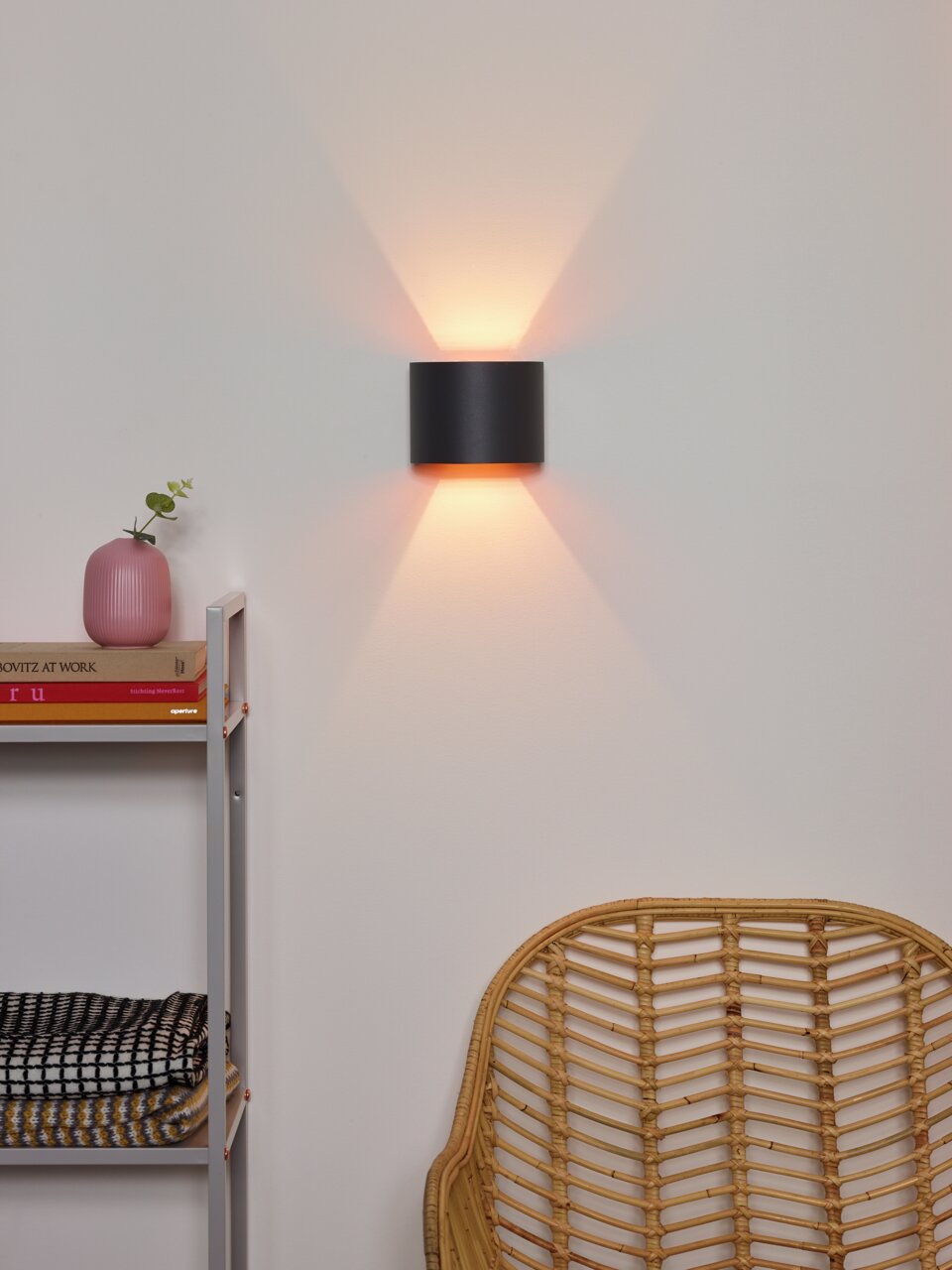 Moderne Wandleuchte XIO in schwarzem Design, die warmes Licht nach oben und unten abstrahlt, seitliche Perspektive.