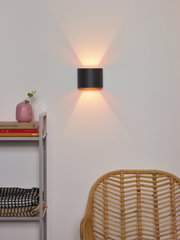 Moderne wandlamp XIO in zwart, die warm licht naar boven en beneden verspreidt, zijaanzicht.