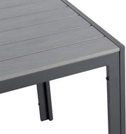 Nahaufnahme eines Gartentisches mit grauer Tischplatte und Metallrahmen, Perspektive von oben auf die Ecke.