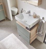 Moderner Waschbeckenunterschrank mit zwei Schubladen in Holzoptik und grünlichen Fronten, von oben fotografiert.