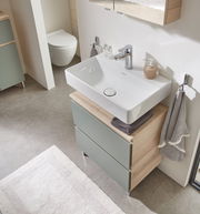 Moderner Waschbeckenunterschrank mit zwei Schubladen in Holzoptik und grünlichen Fronten, von oben fotografiert.