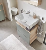 Moderner Waschbeckenunterschrank mit zwei Schubladen in Holzoptik und grünlichen Fronten, von oben fotografiert.