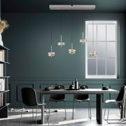 Moderne Pendelleuchte Q-ROTATE mit vier verstellbaren Leuchten über einem Esstisch, seitliche Perspektive.