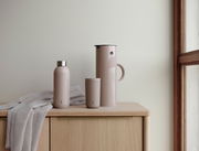 EM77 Isolierkanne, 1L, heather, in Seitenansicht auf einem Holztisch neben einer passenden Trinkflasche und einem Becher.