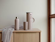 EM77 Isolierkanne, 1L, heather, in Seitenansicht auf einem Holztisch neben einer passenden Trinkflasche und einem Becher.