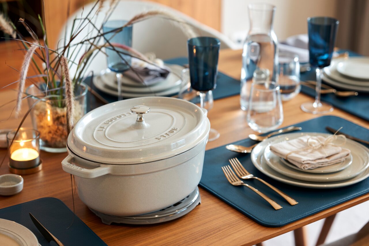 Eleganter weißer ovaler Bräter Cocotte 33cm auf einem gedeckten Tisch, seitliche Perspektive.