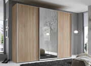 Schwebetürenschrank in Holzoptik mit Spiegel in einem modernen Schlafzimmer, seitliche Perspektive.