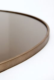 Nahaufnahme eines runden Spiegels mit bronzefarbenem Rahmen, seitliche Perspektive.