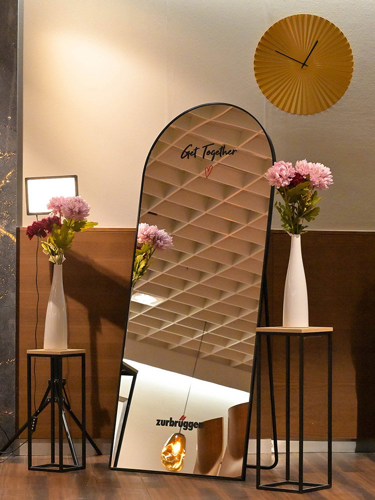 Grote staande spiegel met ‘Get Together’-tekst, sfeervol gecombineerd met roze bloemen en moderne bijzettafels.