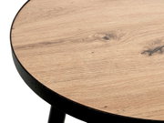 Nahaufnahme einer runden Tischplatte in Holzoptik mit schwarzem Metallrahmen, schräg von oben fotografiert.