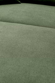 Nahaufnahme der grün melierten Stoffpolsterung eines Sofas mit sichtbarer Sitz- und Rückenfläche, fotografiert aus leicht schräger Draufsicht.