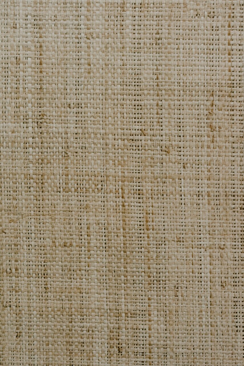 Nahaufnahme einer gewebten Textur in natürlichen Beigetönen, von oben betrachtet.