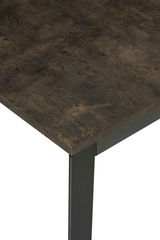 Nahaufnahme eines Esstisches mit dunkler, strukturierter Tischplatte und schwarzem Metallbein, Perspektive von oben.