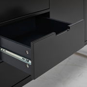 Nahaufnahme einer geöffneten Schublade eines schwarzen Sideboards, seitliche Perspektive