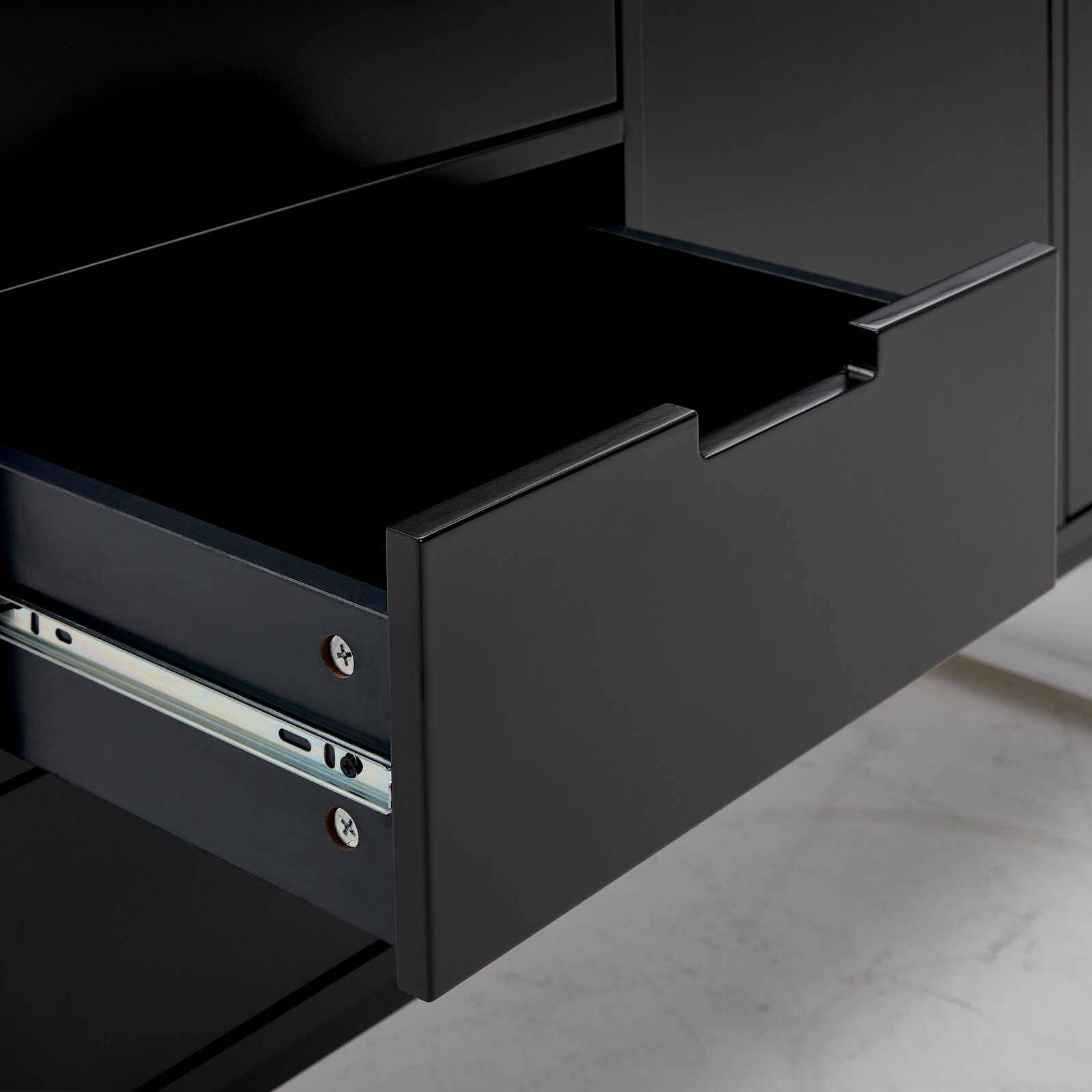 Nahaufnahme einer geöffneten Schublade eines schwarzen Sideboards, seitliche Perspektive