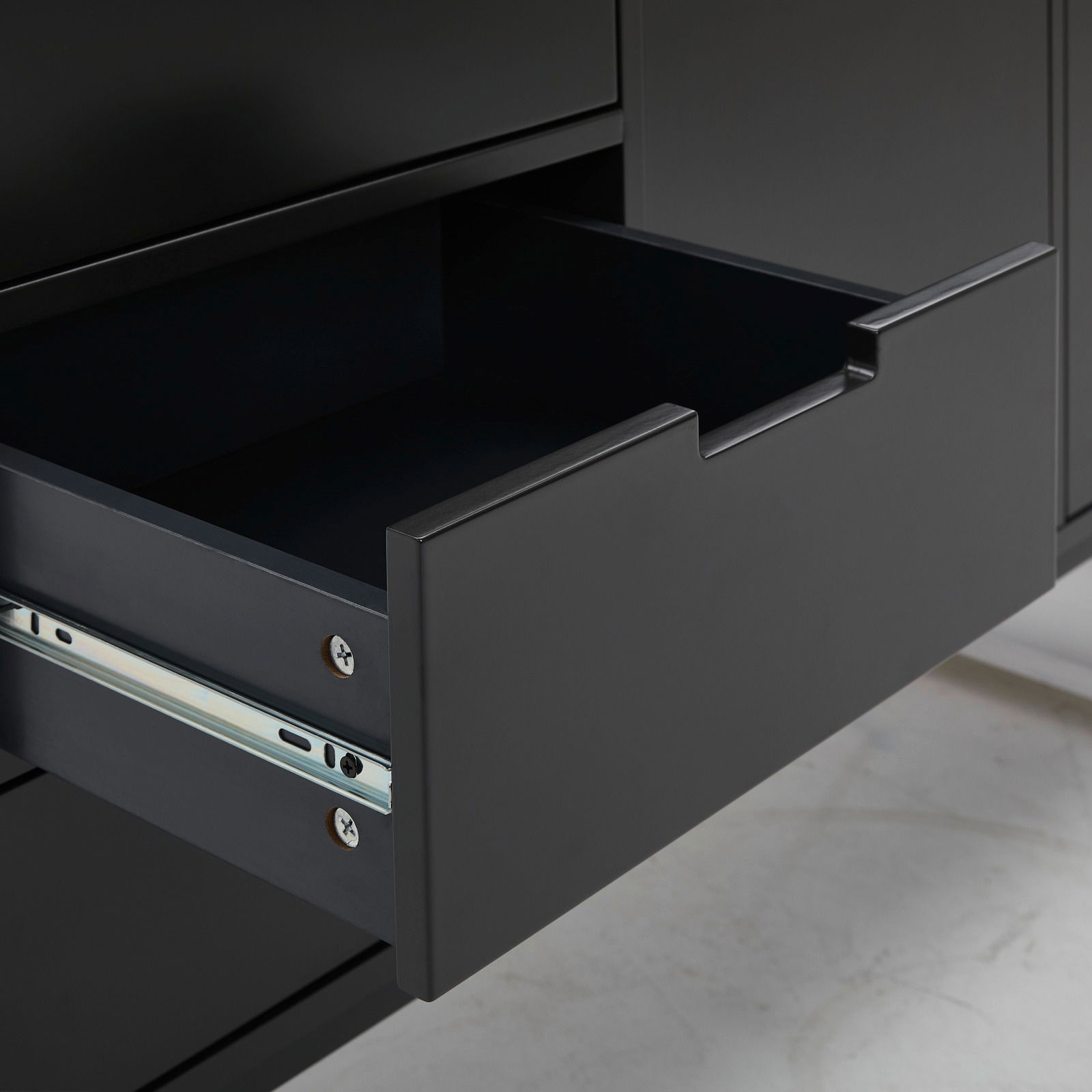 Nahaufnahme einer geöffneten Schublade eines schwarzen Sideboards, seitliche Perspektive