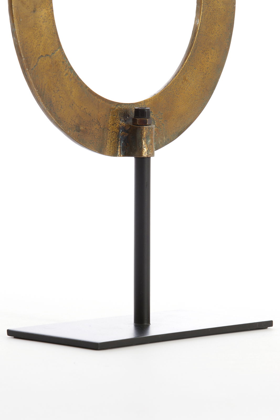 Nahaufnahme eines metallischen Ornaments in Ringform auf einem schwarzen Ständer, seitliche Perspektive.