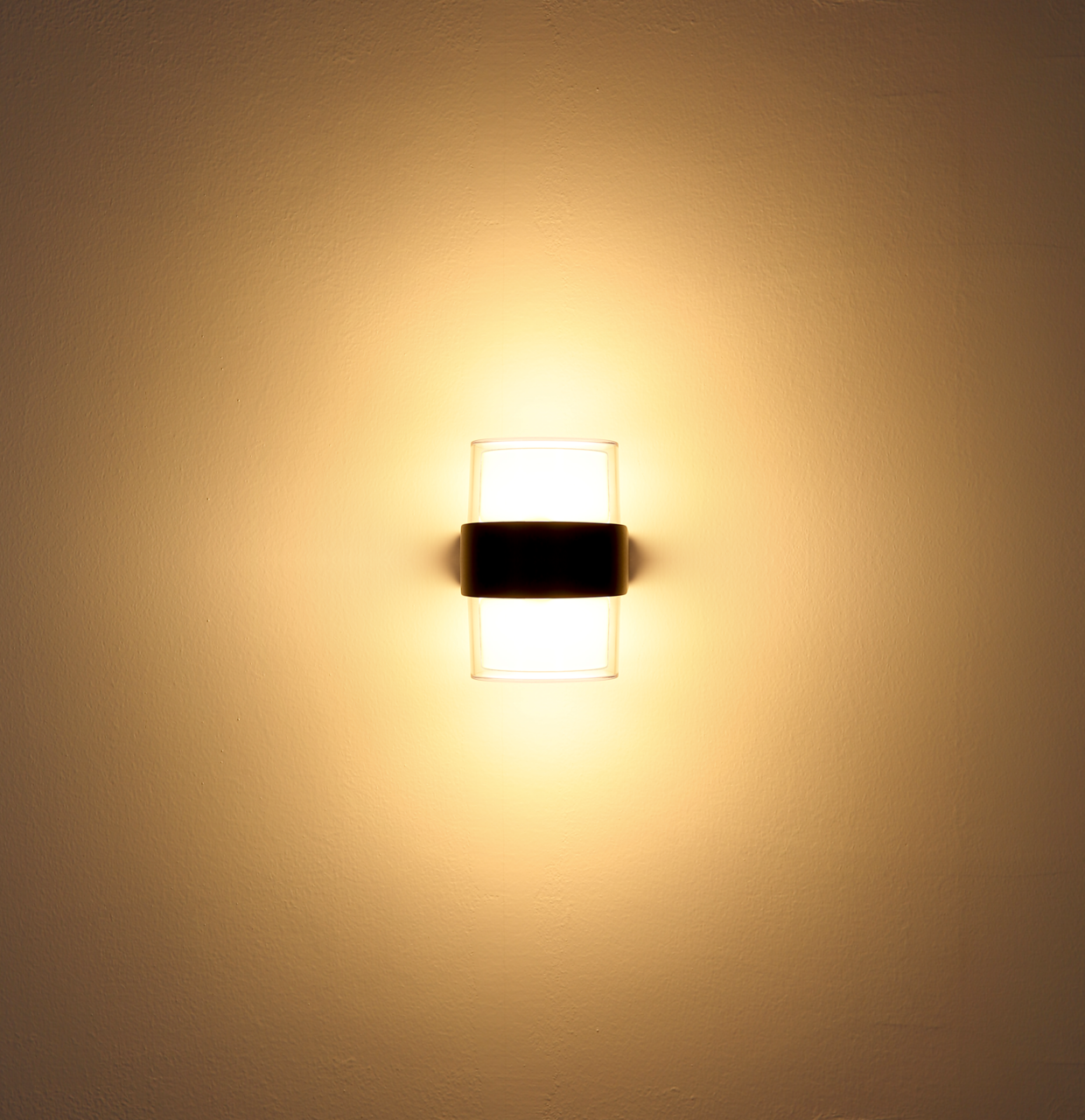 LED-Außenwandleuchte, frontal an der Wand montiert, mit warmem Lichtschein.