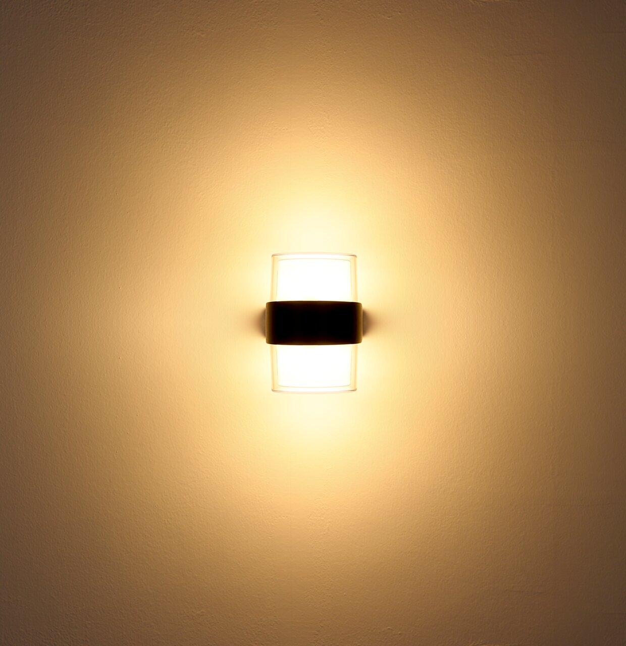 LED-Außenwandleuchte, frontal an der Wand montiert, mit warmem Lichtschein.