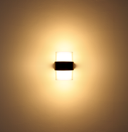 LED-Außenwandleuchte, frontal an der Wand montiert, mit warmem Lichtschein.