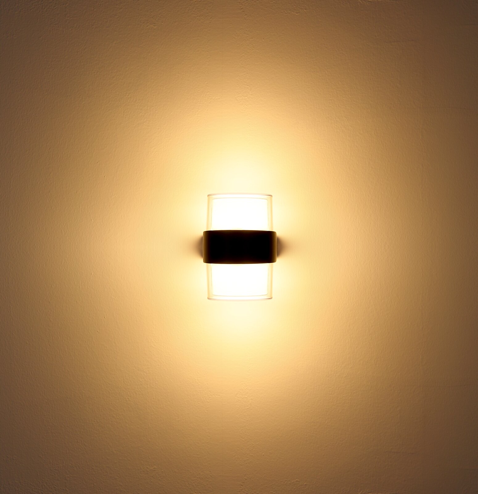 LED-Außenwandleuchte, frontal an der Wand montiert, mit warmem Lichtschein.