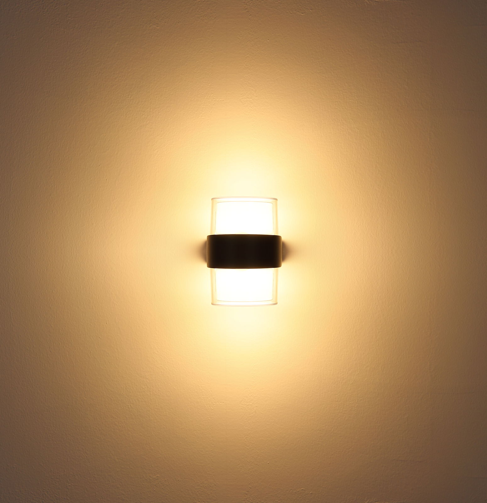 LED-Außenwandleuchte, frontal an der Wand montiert, mit warmem Lichtschein.