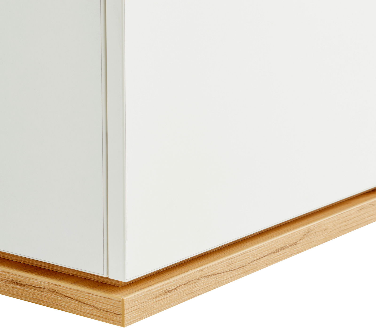 Nahaufnahme einer weißen Kommode mit Holzsockel, seitliche Perspektive.