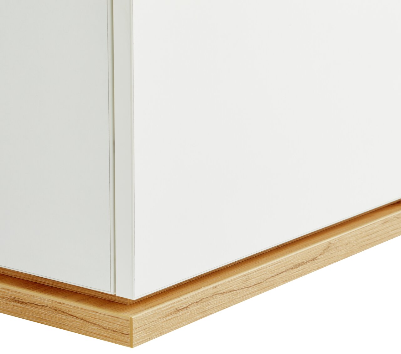 Nahaufnahme einer weißen Kommode mit Holzsockel, seitliche Perspektive.