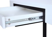 Nahaufnahme eines weißen Couchtischs mit einer geöffneten Schublade und schwarzem Metallrahmen, seitliche Perspektive.