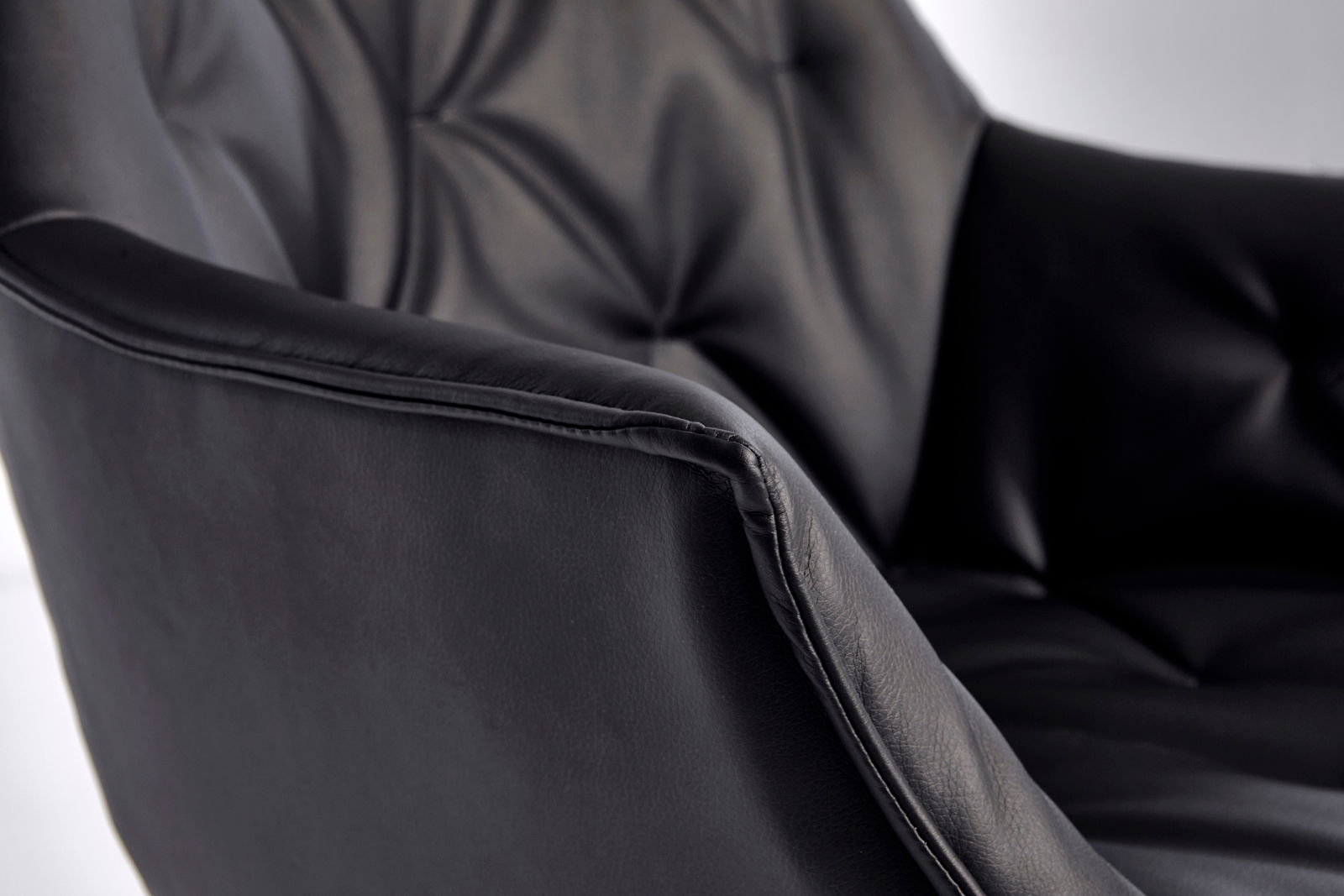 Nahaufnahme eines schwarzen Bürostuhls mit gepolstertem Lederbezug und eleganter Steppung, seitliche Perspektive