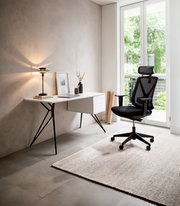 Moderner Schreibtisch mit schlanken Metallbeinen und Schubladen, daneben ein ergonomischer Bürostuhl, in einem hellen Raum mit Blick auf einen Garten.