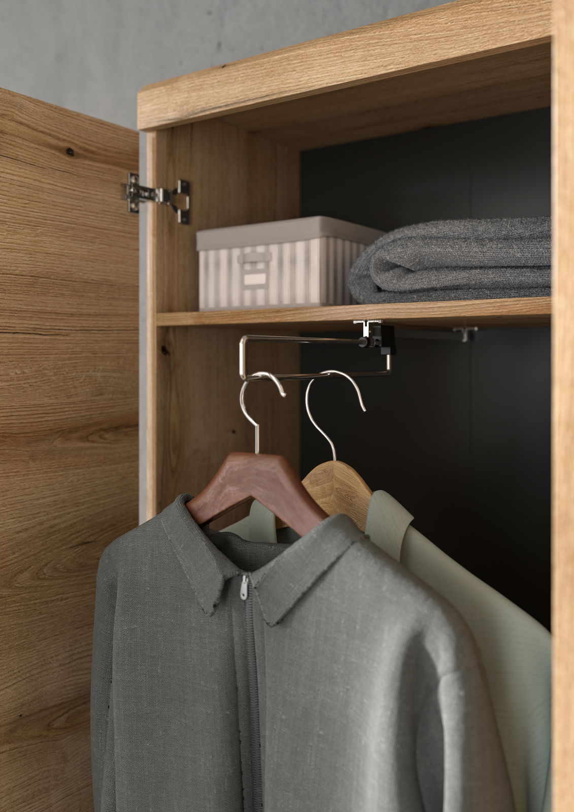 Nahaufnahme eines offenen Holzschranks mit Kleiderstange, auf der zwei Kleiderbügel mit Hemden hängen. Oben im Schrank befinden sich eine gefaltete Decke und eine Aufbewahrungsbox.