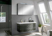 Moderne Badezimmermöbel mit Spiegelschrank und Waschbeckenunterschrank in einer hellen, stilvollen Umgebung, seitliche Perspektive.